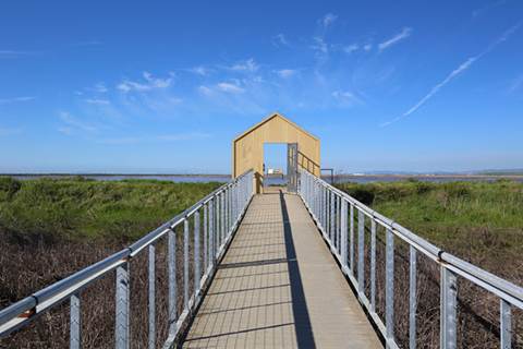 Walking bridge leading to bay surrounded by grass.