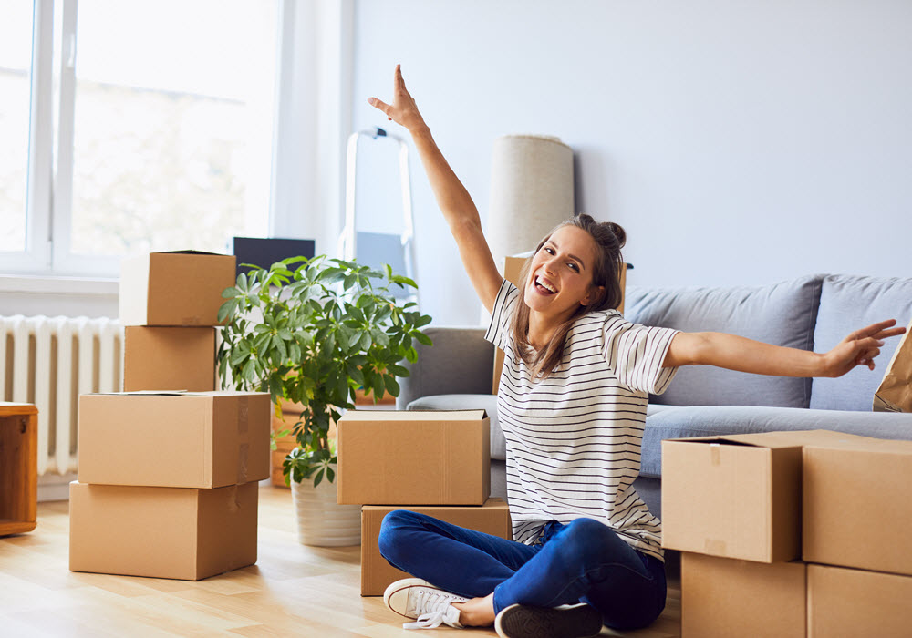 Happy young woman in apartment with moving boxes.