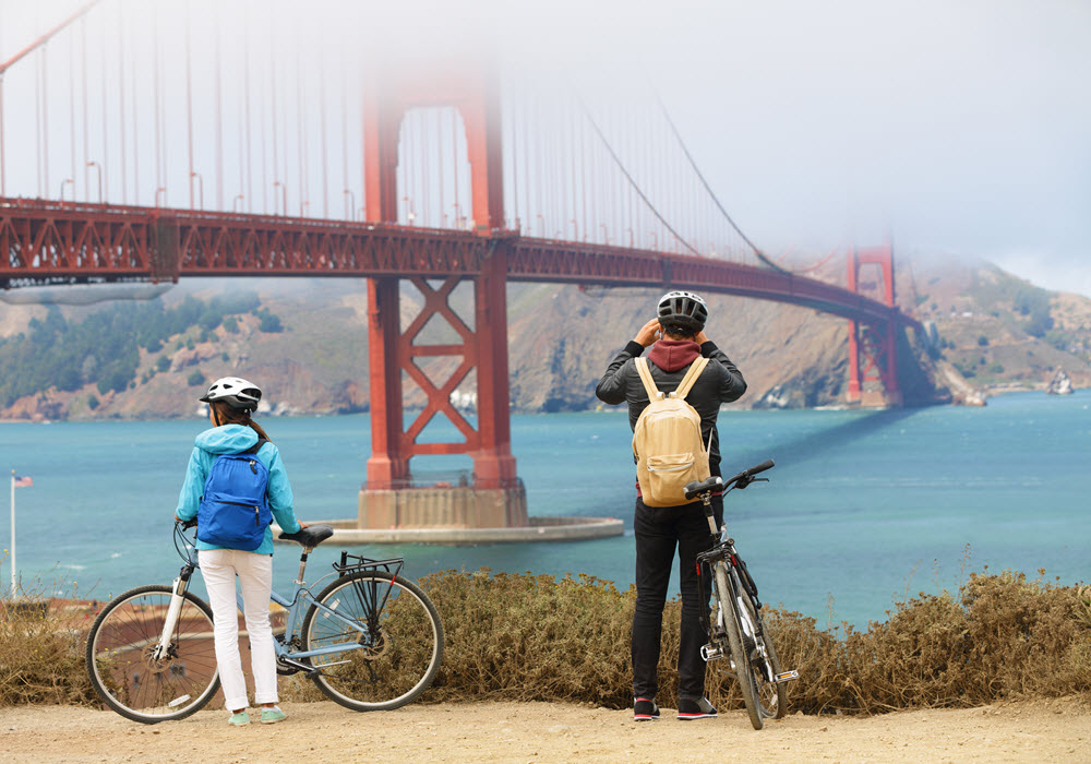 Biking couple looking at the Golden Gate Bridge in San Francisco, California. 