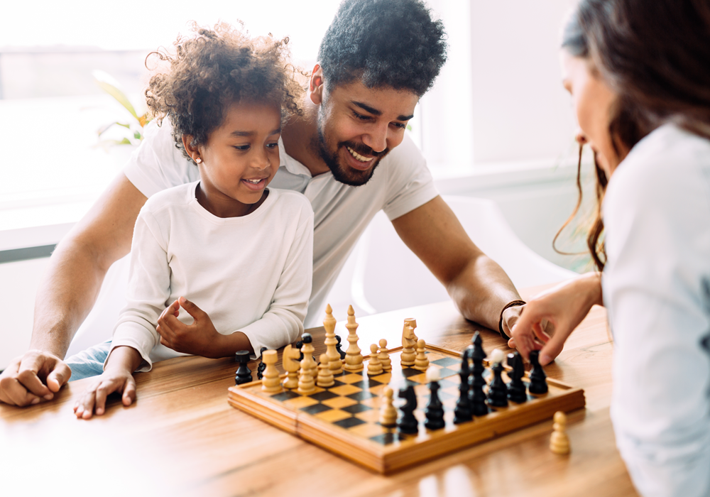 Family of three playing a game of chess in their apartment home.