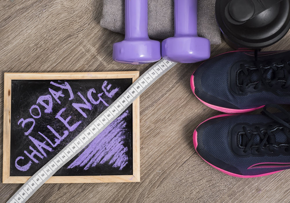 Staged 30-day challenge chalk board surrounded by fitness products.