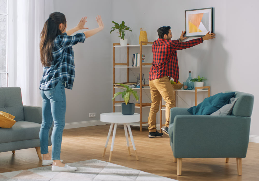 Couple hanging pictures on their apartment wall.