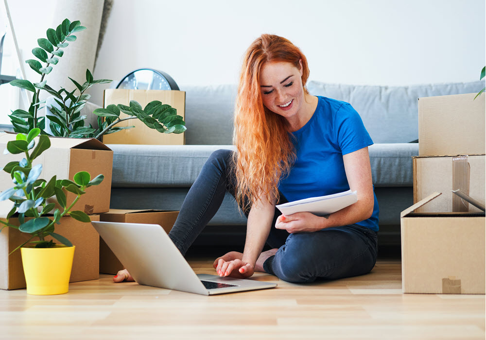 College grad researching on her laptop in her apartment living room.