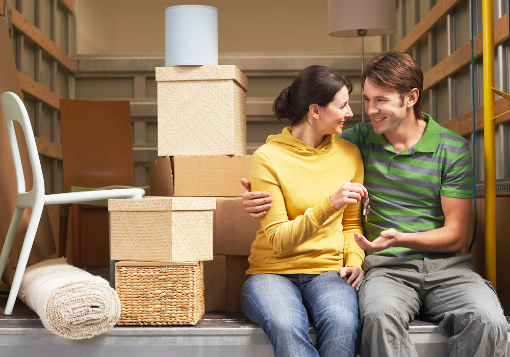 Couple sitting in moving truck next to their moving boxes.