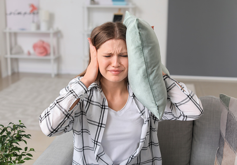 Young woman suffering from loud noise at home