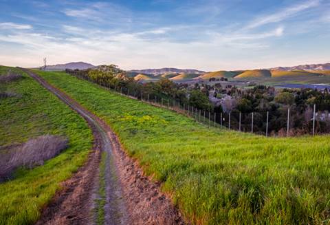 Dirt bike route surrounded by grass with rolling hills in background.