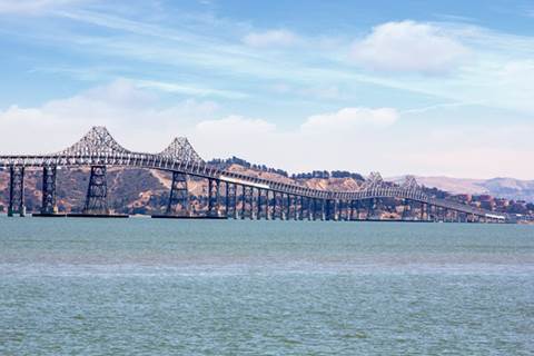 Bridge surrounded by body of water with mountain range in background.