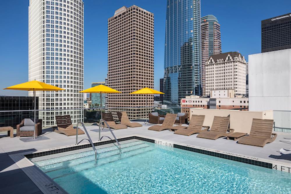 Outdoor swimming pool area with sundeck, lounge seating, and umbrellas.