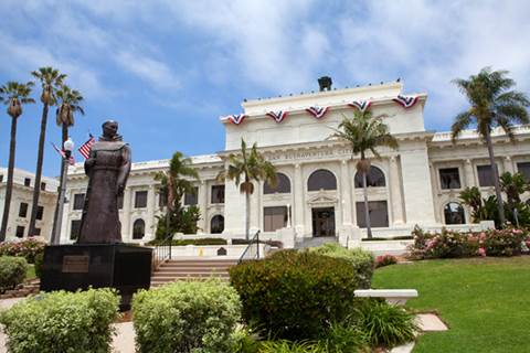 Exterior of San Buenaventura City Hall with landscaping and statue.