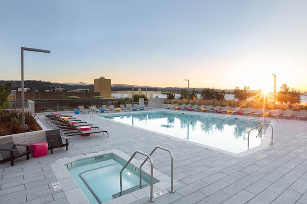 Outdoor spa and swimming pool area with sundeck and lounge seating at sunset.