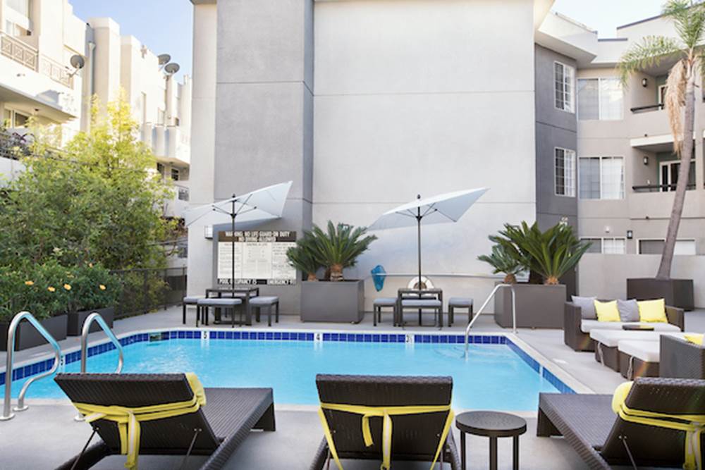 Outdoor swimming pool area with lounge seating, tables, and umbrellas.