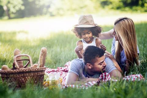 Family of three having a picnic on grass.